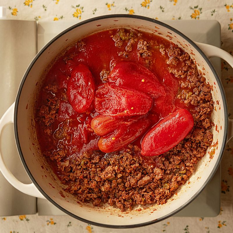 소스 재료, 홀 토마토, 따뜻한 물을 넣어 으깨가며 저어주세요. 
(tip. 꼭 따뜻한 물을 넣어주세요. 찬물을 넣으면 다시 온도가 올라가는 데 시간도 걸리고 음식의 맛도 떨어져요.)
월계수 잎과 허브가루를 넣고 중간 불에서 끓여주세요. 보글보글 끓기 시작하면 약한 불로 줄여 30~40분 정도 저어가며 끓여주세요.
(tip. 살짝 꾸덕꾸덕해질 때까지 뭉근하게 끓여주시면 돼요)
(tip. 기호에 따라 소금으로 간을 조절해 주세요. 페퍼론치노를 넣어 만드시면 매콤하게 드실 수 있답니다)