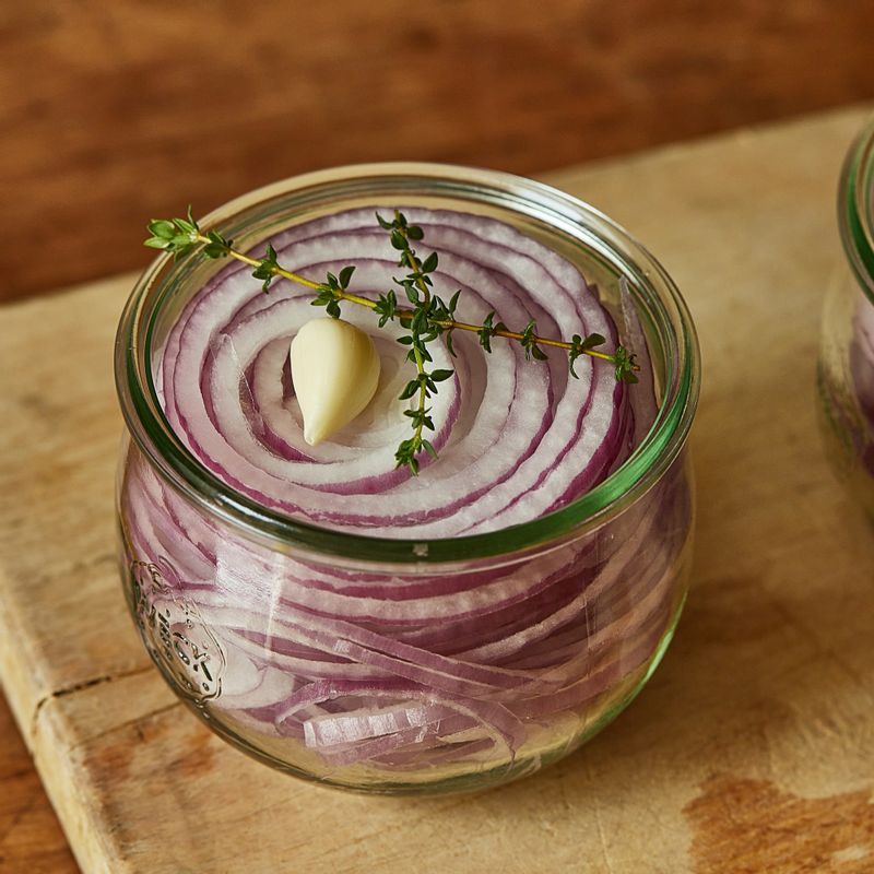 소독한 유리병에 양파와 마늘을 넣고 끓인 피클주스를 뜨거울 때 부어주세요. (tip.피클링 스파이스를 체에 걸러낸 후 부으면 먹을 때 편리해요.)