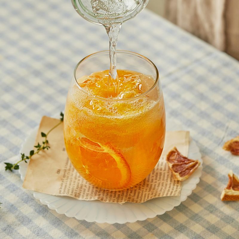 컵에 장식용 오렌지 조각을 넣고 얼음을 넣어주세요. 오렌지 주스를 컵의 반 정도 채우고 시원한 탄산수를 부어주세요.