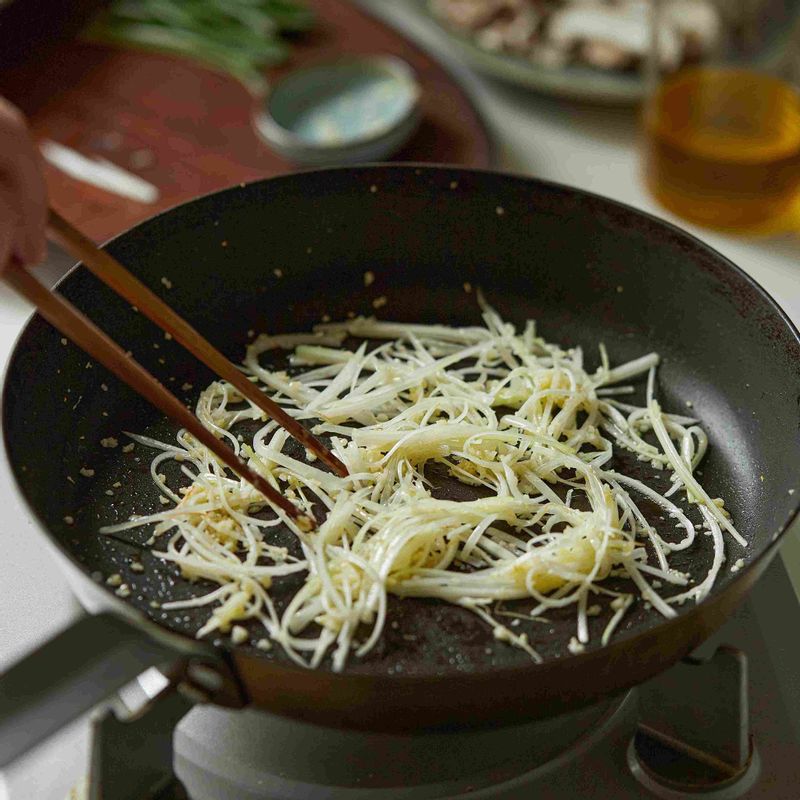 달군 팬에 식용유를 넉넉히 두르고 다진 마늘과 대파 흰 부분을 넣어 볶아주세요.