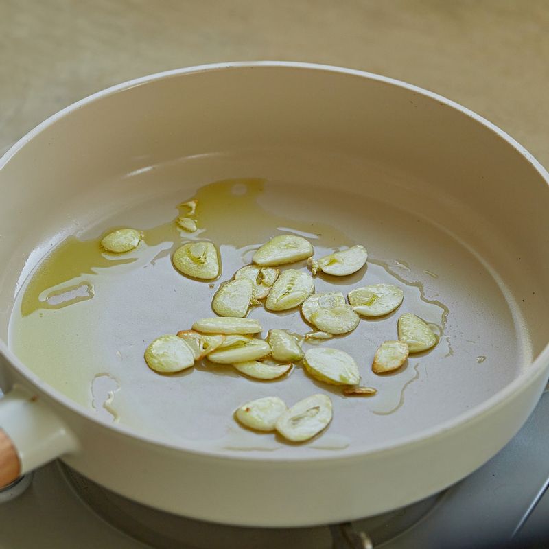 달군 팬에 올리브유 3큰술을 두르고 마늘을 넣어 약한 불에서 노릇하게 볶아주세요.