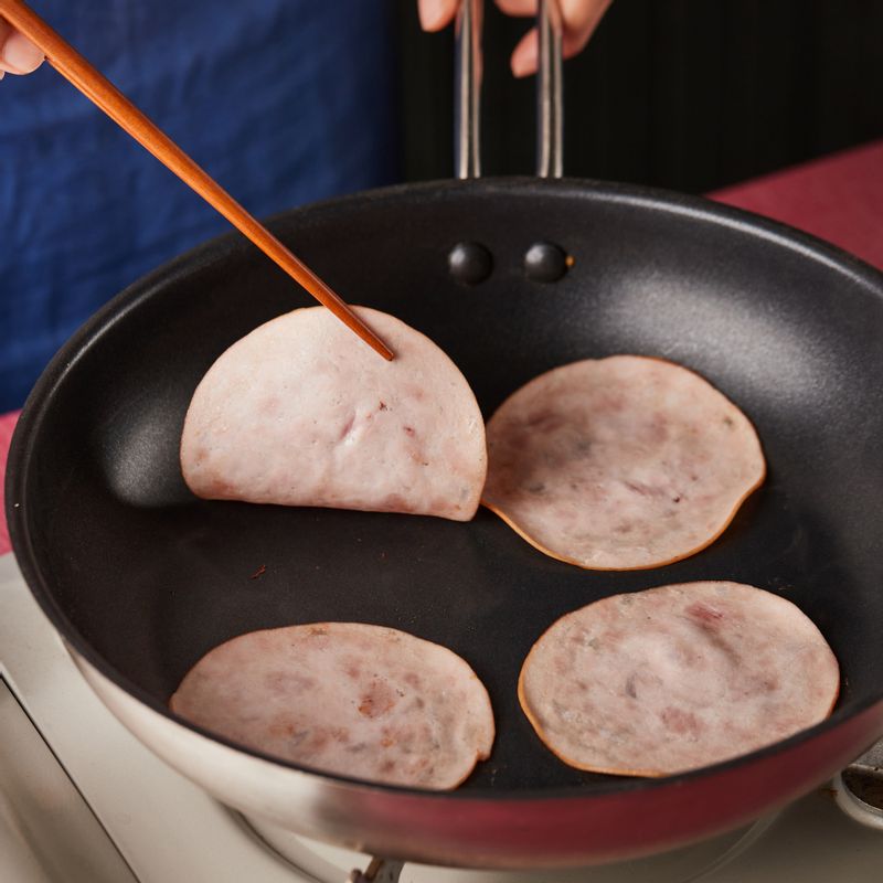 달군 팬에 슬라이스 햄을 살짝 굽고 그릇에 덜어 준비해 주세요. 팬에 식용유를 살짝 두르고 캔 옥수수를 넣어 볶아 물기를 제거해 주세요.