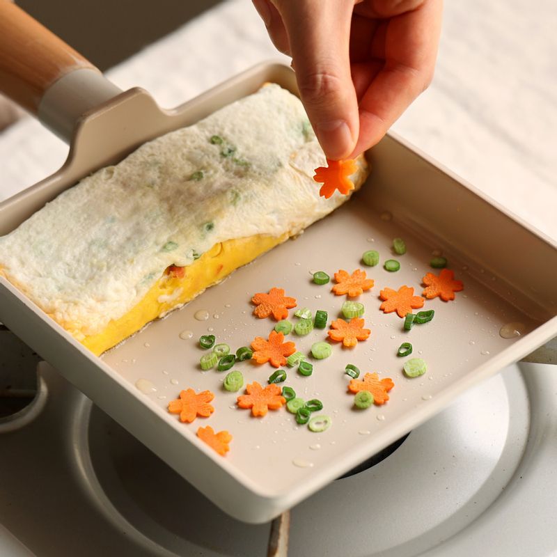 말아진 달걀을 팬 아래쪽으로 밀어 놓고, 팬에 꽃 모양 당근과 쪽파를 얹고 흰자를 부어 돌돌 말아주세요.