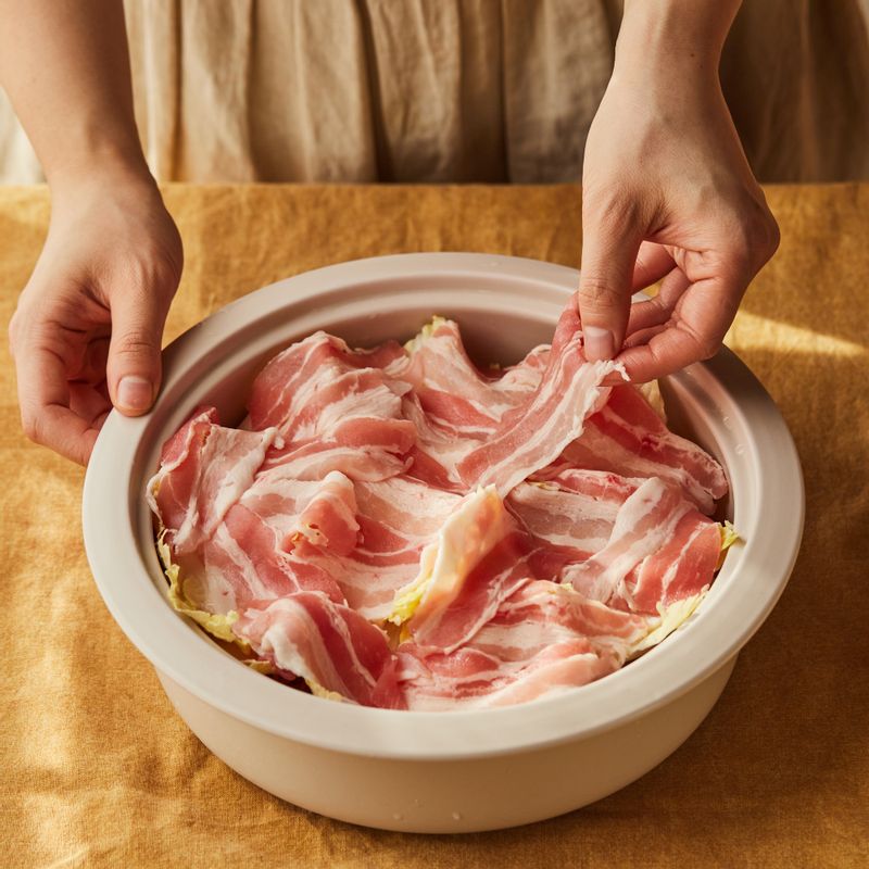 내열 용기에 알 배추의 두꺼운 줄기 부분을 깔고 숙주 - 알배추 - 삼겹살 순으로 올리고 약간의 소금과 후춧가루를 뿌려주세요. 먹기 좋게 켜켜이 돌려 담고 화이트와인을 부어주세요.
(tip.화이트와인 대신 청주를 사용해도 좋아요.)