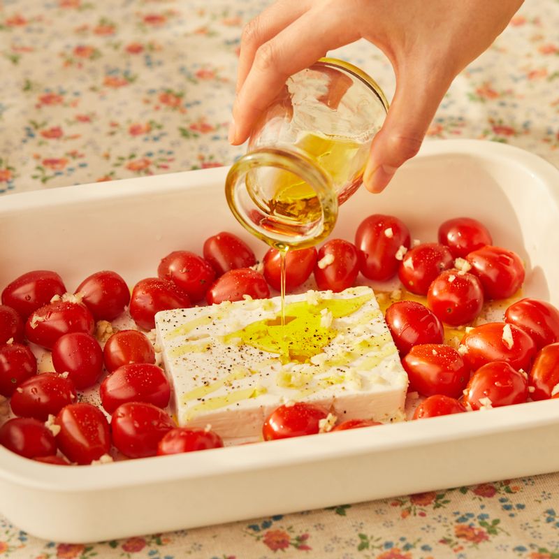 내열 용기에 페타치즈와 방울토마토를 담고 소금과 후춧가루, 다진 마늘, 올리브오일을 넣어주세요.