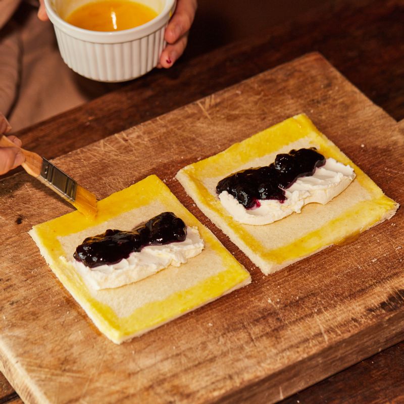 식빵 테두리에 달걀 물을 발라 접어주고, 포크로 테두리를 눌러 양쪽 면을 붙여주세요.