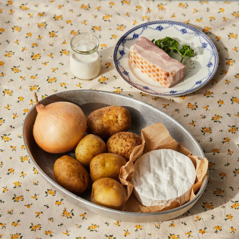 타르티플레트을 위한 재료 이미지로 감자,까망베르 치즈,양파,두꺼운 베이컨,버터 등으로 구성 되어있습니다.