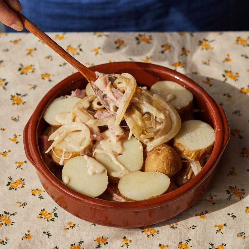 내열 용기에 버터를 약간 바른 후 감자를 깔고 볶은 베이컨과 감자 순으로 쌓은 후 까망베르 치즈를 올려주세요.