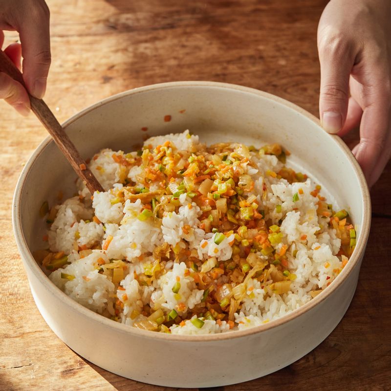 따뜻한 밥에 볶은 야채와 참기름, 통깨를 넣고 골고루 섞은 후 한 입 크기로 동그랗게 모양을 잡아 주먹밥을 만들어주세요.