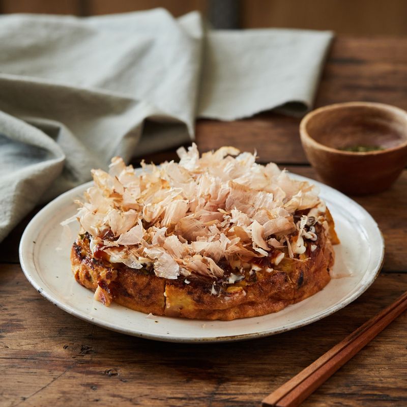 구운 오코노미야키를 먹기 좋게 썰어 접시에 담고 돈가스 소스와 마요네즈를 뿌리고 파래 가루와 가쓰오부시를 올려 완성해 주세요.