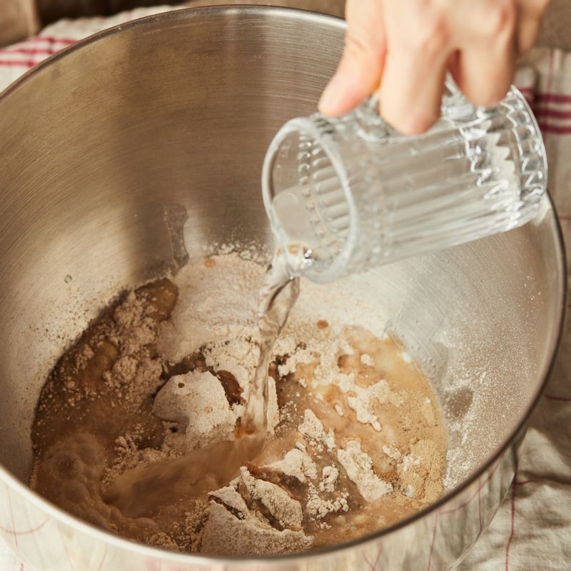 반죽기에 통밀가루, 소금, 이스트 섞은 따뜻한 물, 포도 씨 오일, 꿀을 넣고 저속으로 5분, 중속으로 10-15분 반죽해 주세요.