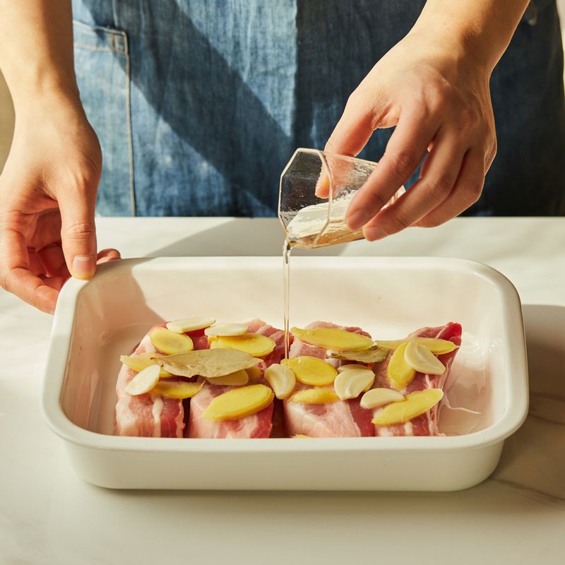 생강과 마늘은 편 썰어주세요. 내열 용기에 통 삼겹살을 올리고 생강, 마늘, 월계수 잎, 청주를 넣어 20분간 재워주세요.
