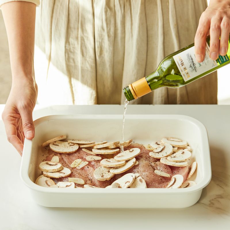 내열 용기에 닭가슴살과 마늘, 양송이버섯을 넣고 소금, 후춧가루, 화이트 와인을 뿌려 밑간하고 생크림과 파마산 치즈를 넣어주세요.