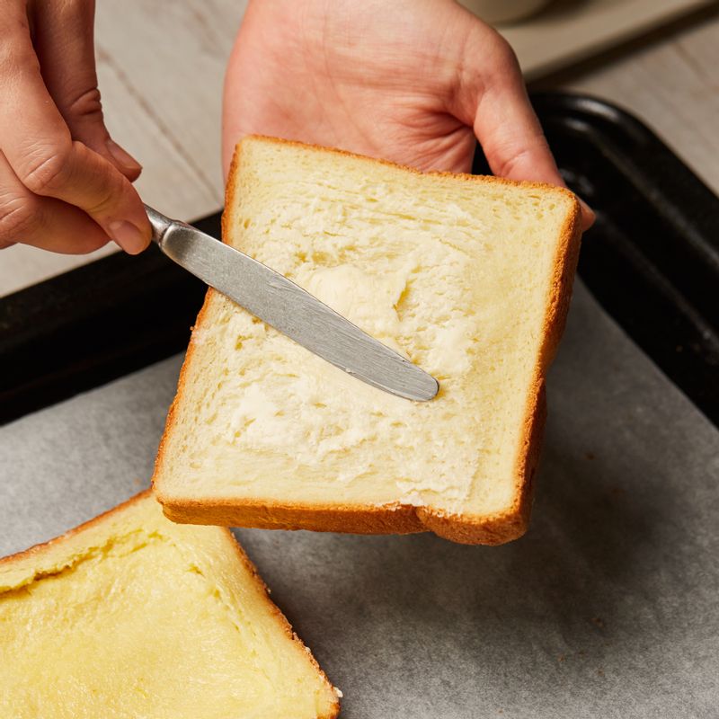 식빵 한 쪽 면에 버터를 바른 후 버터면이 바닥으로 가도록 법랑 접시에 올려주세요. 숟가락으로 식빵의 가장자리 1cm 정도를 남기고 눌러주세요.