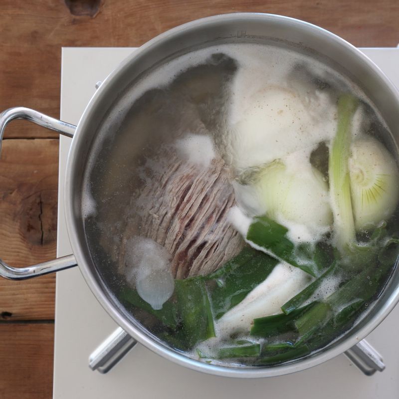 냄비에 핏물을 뺀 쇠고기와 큼직하게 썬 대파, 양파, 무 그리고 고기가 잠길 정도의 물을 넣어 15분간 끓인 후 무만 건져 나박하게 썰어주세요. 1시간 더 삶아 국물은 체에 걸러두고 쇠고기는 결대로 찢습니다.
(쇠고기는 미리 찬물에 30분간 담가 핏물을 빼주세요.)