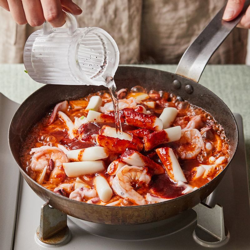 볶은 해물에 양파를 넣고 볶다가, 양념, 떡, 물을 넣어 3분 정도 끓여주세요.