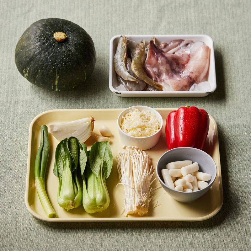 단호박 해물떡찜을 위한 재료 이미지로 단호박(중간 크기),떡볶이 떡,새우,손질 오징어,양파 등으로 구성 되어있습니다.