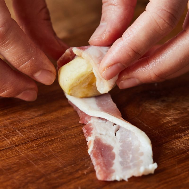 찐 밤을 베이컨으로 돌돌 말아 꼬치로 고정을 시켜 법랑 접시 위에 올려주세요.