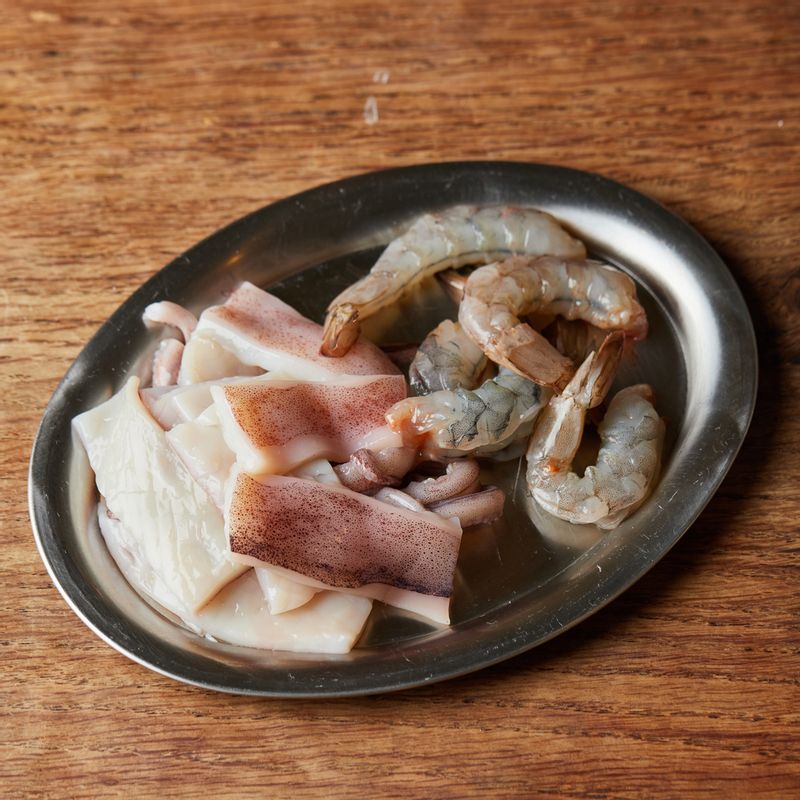 오징어는 칼집을 넣어 먹기 좋게 썰고 새우는 껍질을 까고 등 부분에 칼집을 넣어 내장을 제거해 주세요.