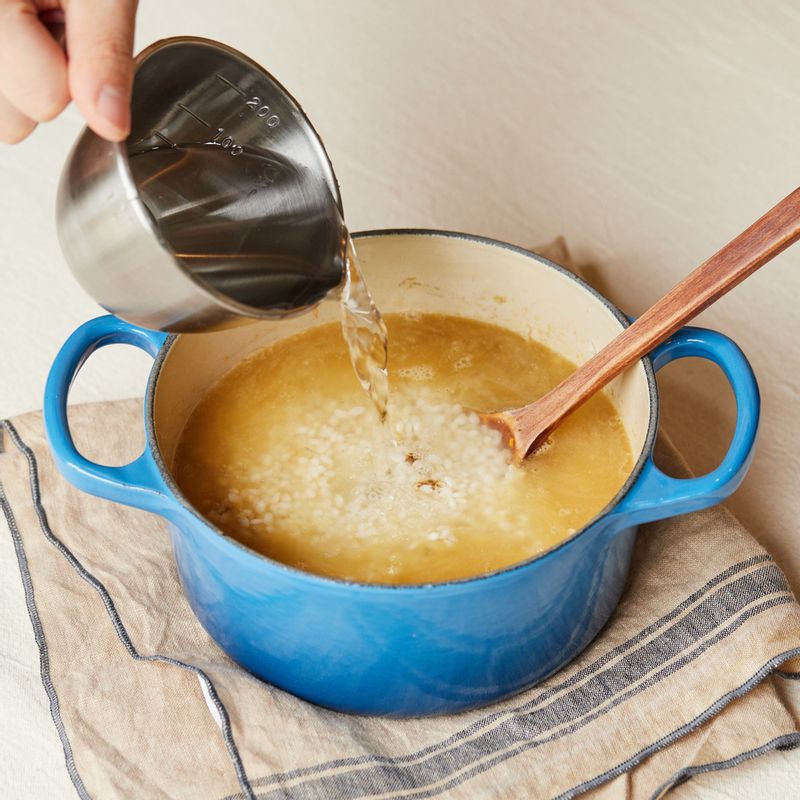 냄비에 참기름을 두르고 불린 쌀과 다진 전복 내장, 맛술을 넣어 3분 정도 볶다가 다시마 육수를 부어주세요.