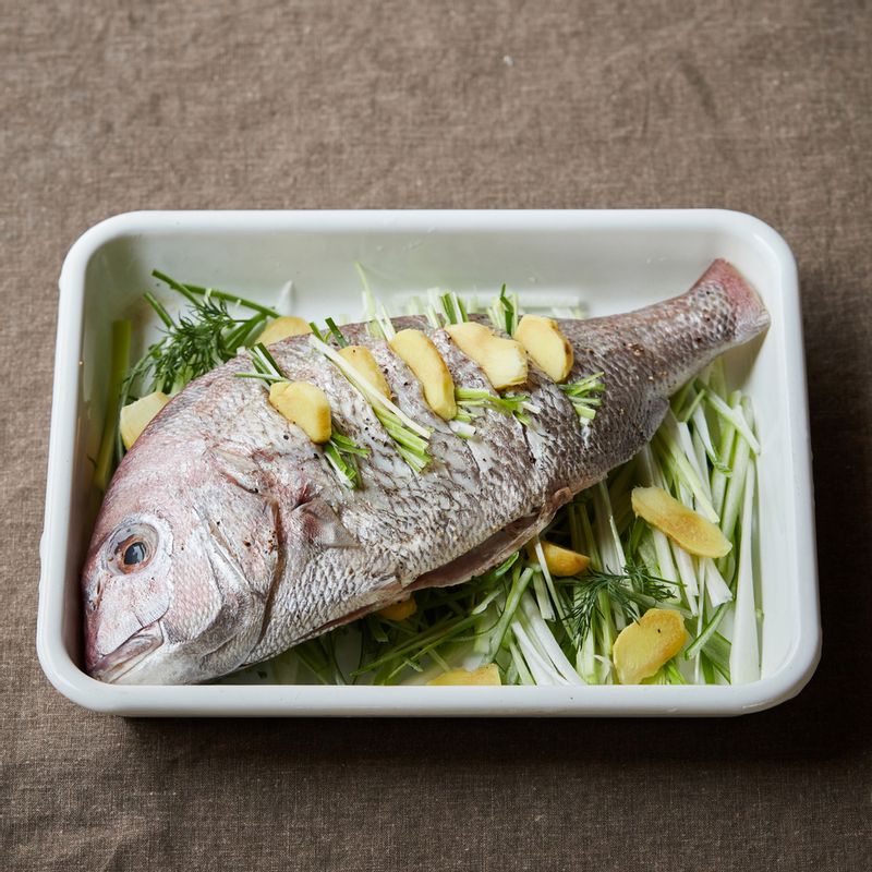 도미 칼집 사이와 뱃속에 생강과 대파를 넣어주세요. 내열 용기에 채 썬 대파 절반과 생강을 깔고 도미를 올려주세요.