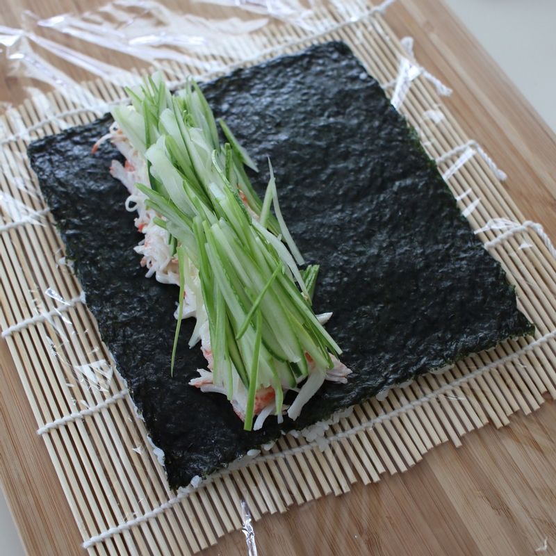 김 위에 게맛살을 올리고 크림치즈를 골고루 올려준 후, 그 위에 오이를 올려주세요.