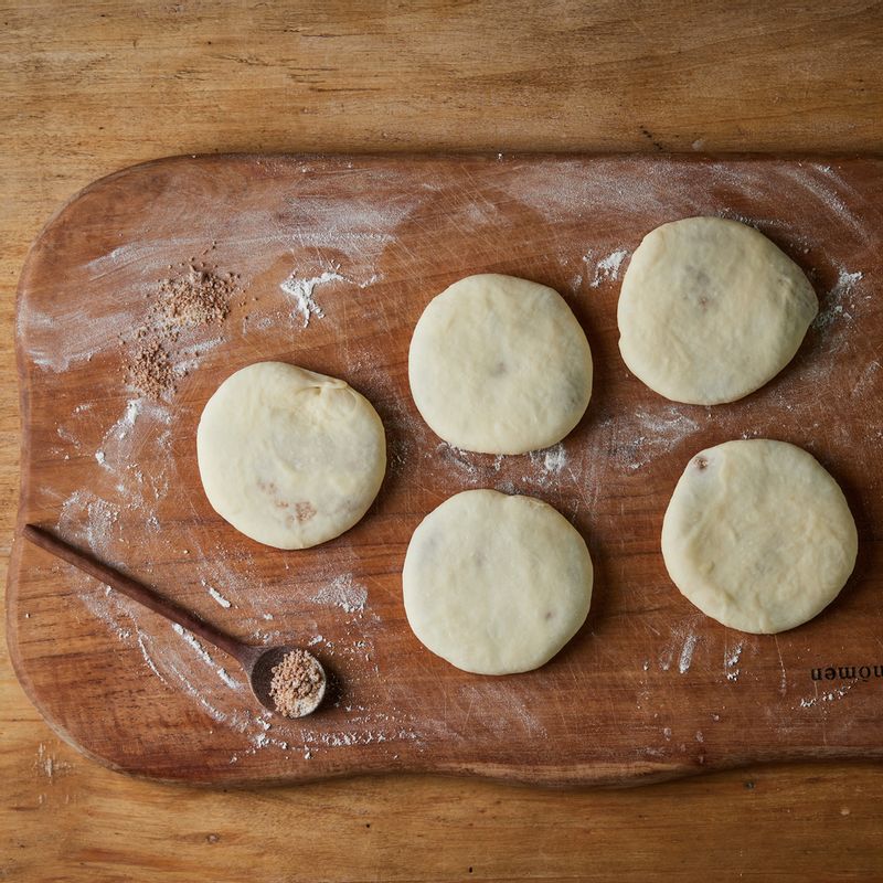 접은 부분이 밑으로 가도록 바닥에 놓고 덧가루를 뿌려가며 속이 터지지 않을 정도로 얇게 밀고 표면에 물을 바른 후 깨를 뿌려주세요.
(tip. 지름 13cm, 두께 3mm 정도가 적당해요)