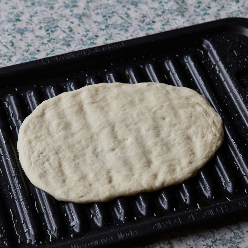 2차 발효가 끝난 반죽을 올리브오일을 바른 구이전용팬에 올려 손으로 가볍게 두들겨 가스를 빼고 둥글게 모양을 잡아주세요.