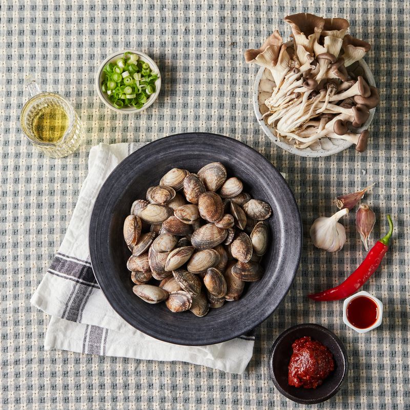 매운 조개 버섯찜을 위한 재료 이미지로 모시조개 또는 바지락,느타리버섯,화이트 와인,송송 썬 쪽파 등으로 구성 되어있습니다.