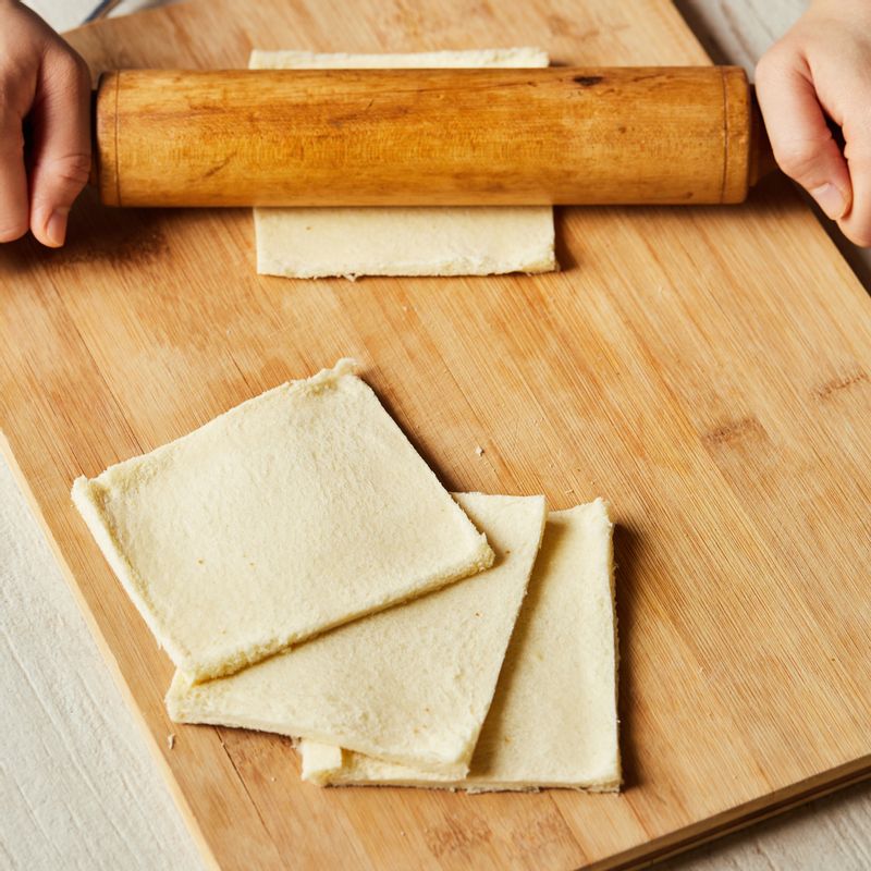 식빵은 테두리를 자르고 밀대를 이용해서 평평하게 밀고, 한쪽 면에 사과 조림을 넣어주세요.