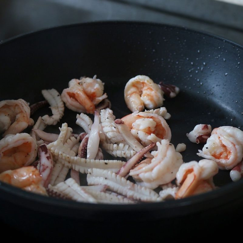 달군 팬에 양파, 청피망, 홍고추, 목이버섯 순으로 넣고 소금으로 간을 해 볶은 후 덜어두세요. 다시 식용유를 두르고 다진 마늘을 볶다가 오징어, 새우를 넣고 소금, 후추로 간을 해 볶아줍니다.