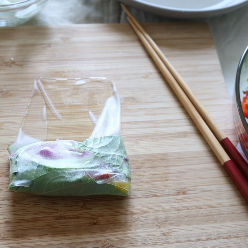 라이스페이퍼의 양 옆을 접고 돌돌 말아 이등분합니다.