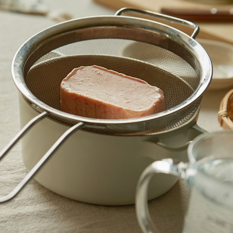 체망에 스팸을 올리고 뜨거운 물을 부어 기름을 제거해주세요.