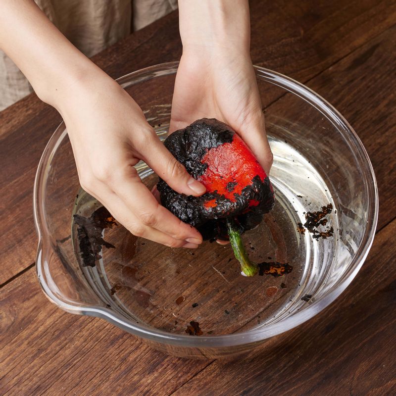 파프리카를 찬물에 담가 문지르면서 겉 껍질을 벗겨내주세요. 반으로 자른 후 속의 씨앗부분과 꼭지 부분을 제거해주세요.