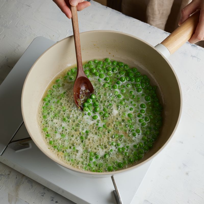 치킨스톡과 물을 넣어 중불에서 완두콩이 충분히 무르게 익도록 볶아주세요. 소금, 후춧가루를 넣어 간을 해주세요.