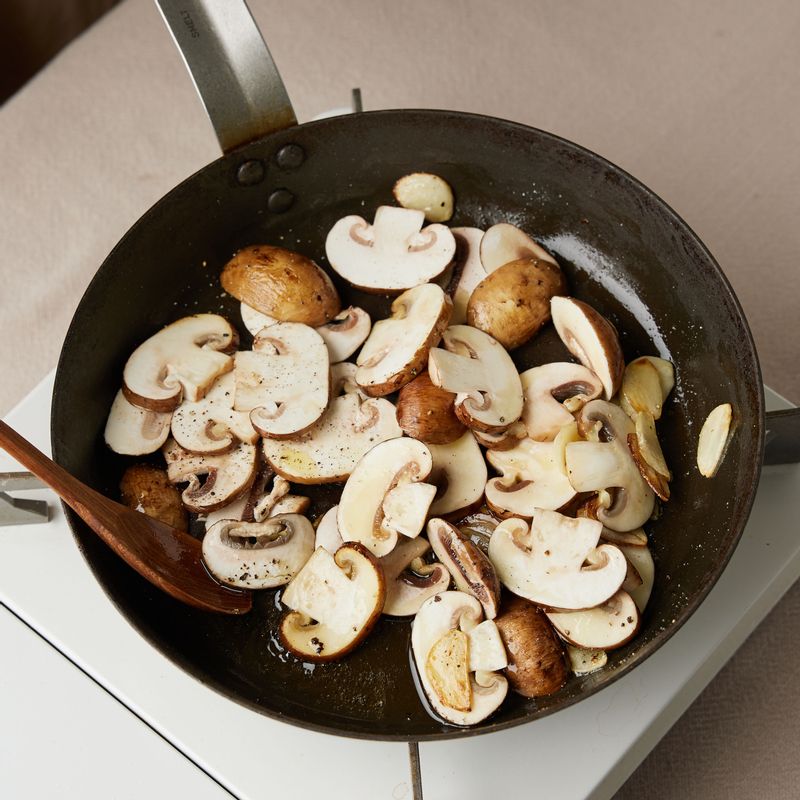달군 팬에 슬라이스한 마늘과 양송이 버섯을 넣어 소금, 후춧가루로 간을 해 노릇하게 볶아주세요.