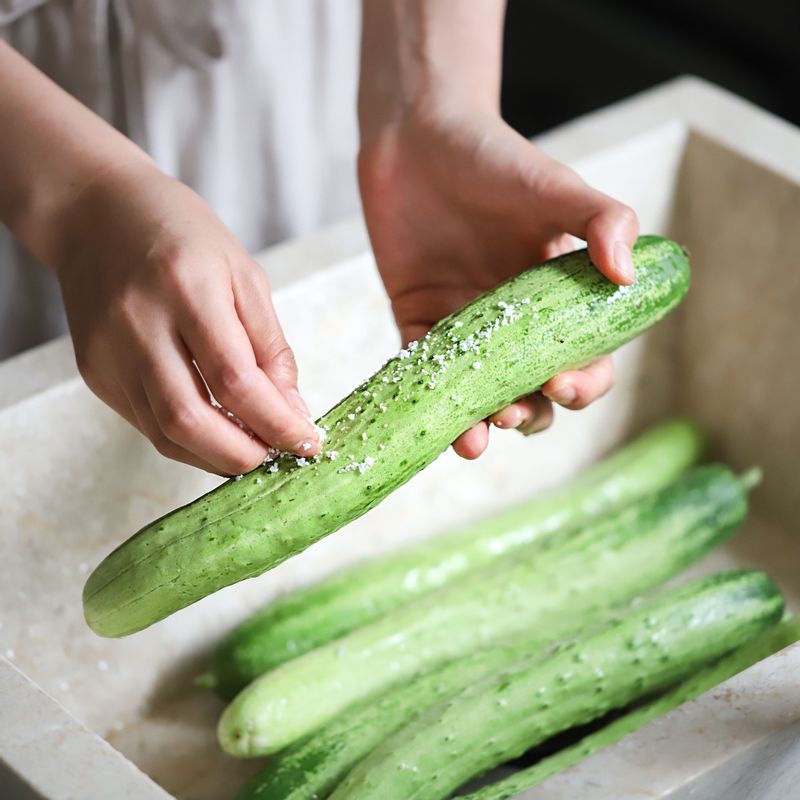오이를 깨끗이 씻어 꽃소금에 문질러 가시를 제거해주세요. 오이의 양쪽 끝을 자르고 3~4등분 한 후 밑동을 1cm가량 남기고, 열십자 모양으로 칼집을 내주세요.