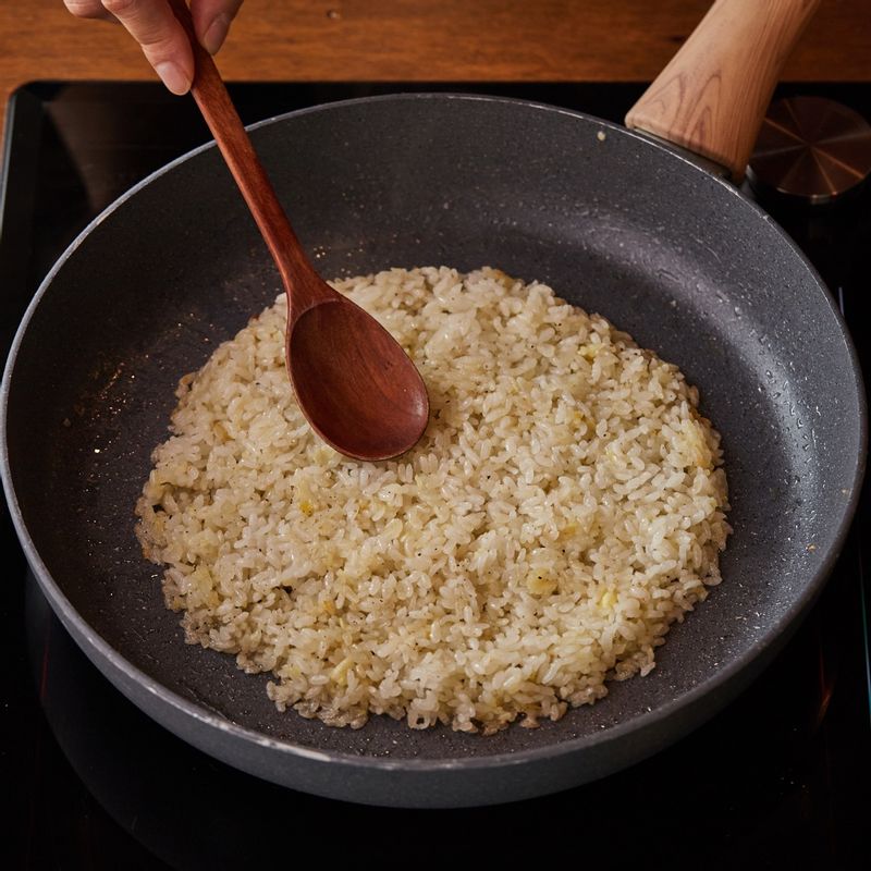 달군 팬에 버터와 다진 마늘을 넣고 볶은 후 밥을 넣고 볶다가 소금 한 꼬집과 후춧가루로 간을 해주세요. 볶은 밥을 꾹꾹 눌러 아래 면을 노릇하게 구워주세요.