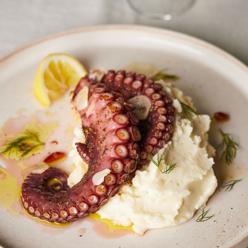 접시에 감자퓨레를 깔고 구운 문어다리를 올린 후 파마산 치즈를 갈아서 뿌리고 딜을 올려 완성해주세요.