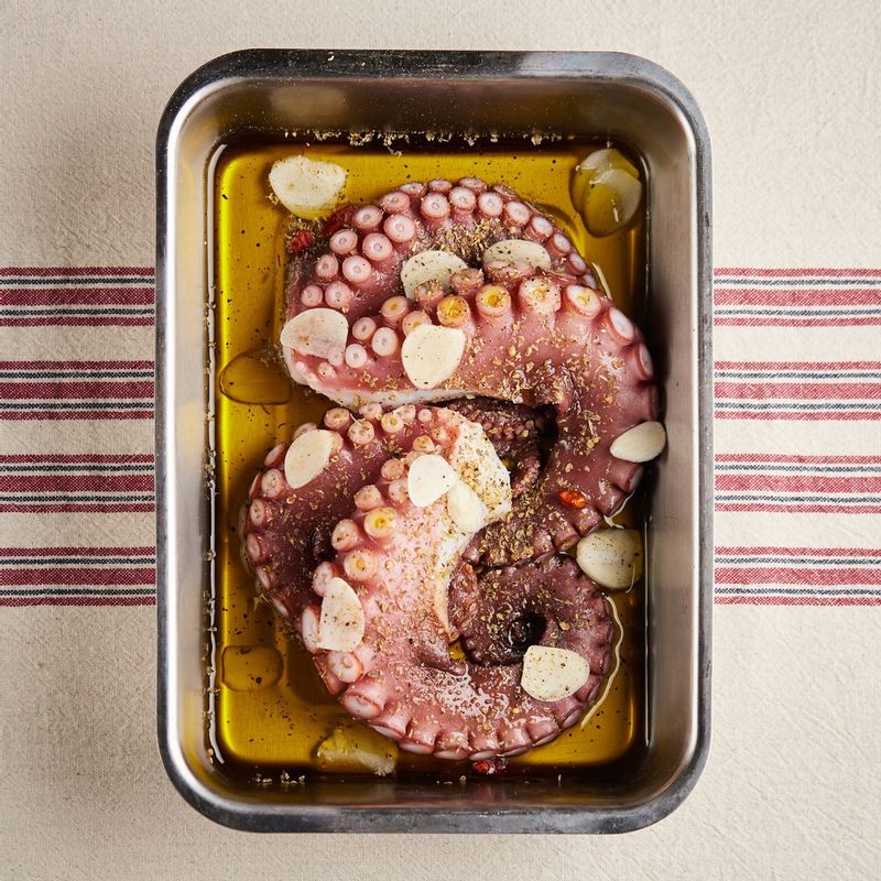 내열 용기에 문어다리와 편썬 마늘, 오레가노, 후추, 올리브오일을 넣고 포일로 감싸주세요.