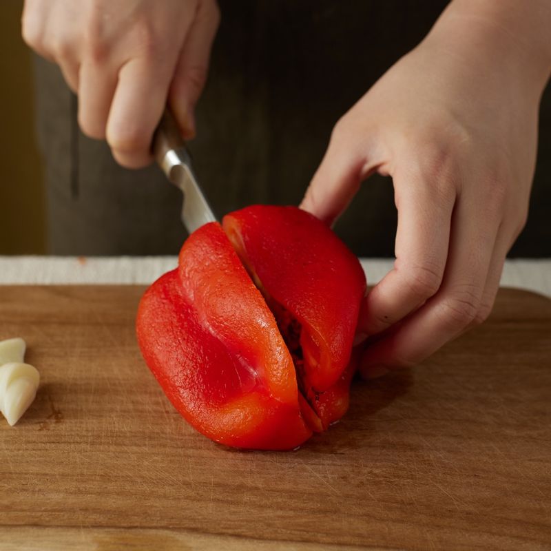 파프리카를 반으로 썬 후 꼭지 부분과 씨를 제거해 주세요. 1cm 두께로 썬 후 소금을 뿌려주세요. 마늘을 얇게 썰어주세요.
