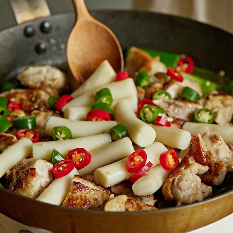 어느정도 익은 닭을 먹기 좋은 크기로 자른 후 떡, 청양고추, 홍고추를 넣어 2분 정도 더 볶아주세요. 준비한 양념을 부어 4~5분 정도 졸여주세요.
(tip. 토치로 겉면을 태우면 불맛을 살릴 수 있어요)