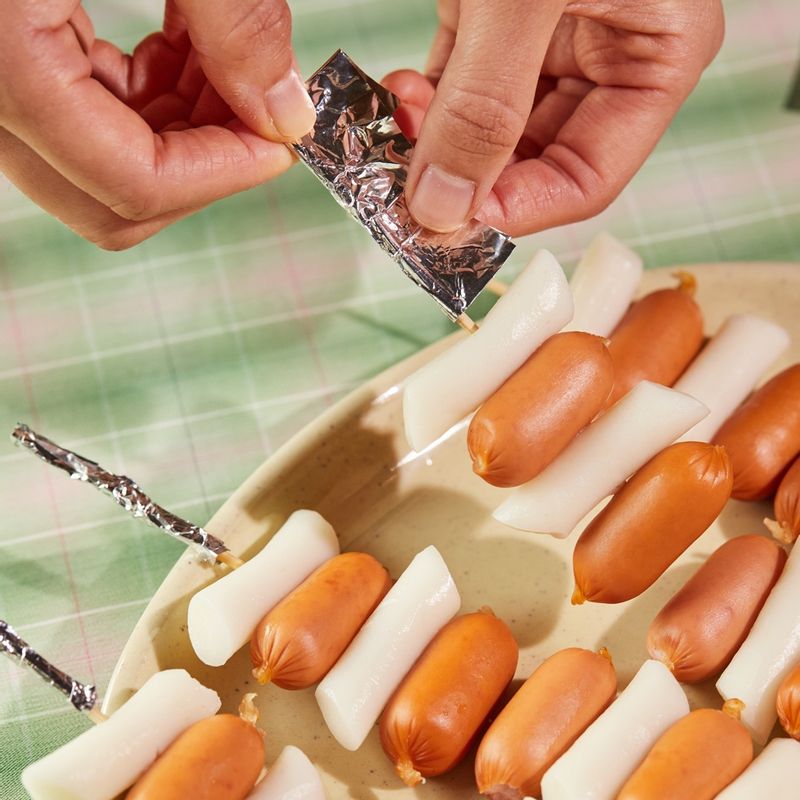 꼬치에 떡과 소시지를 번갈아 가며 끼워주세요. 남은 꼬치 부분을 알루미늄 포일로 감싸주세요.