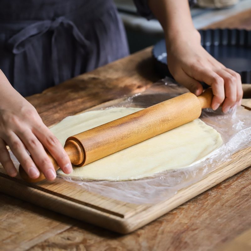 휴지 시킨 반죽을 반으로 나눈 후 바닥용 반죽은 아래위에 비닐을 깔고 평평한 곳에 놓아 밀대를 이용해서 0.3cm가 될 때까지 밀어주세요. 반죽이 비닐에 붙지 않도록 중간중간 양면에 덧밀가루를 뿌려주세요.
파이틀에 반죽을 올려서 조심히 뒤집고 반죽을 손가락으로 눌러 파이틀 안쪽에 붙여주세요.
(tip.파이 반죽을 씌운 파이틀을 냉장고에 30분 정도 더 휴지시켜주면 더 바삭한 파이를 만드실 수 있어요.)