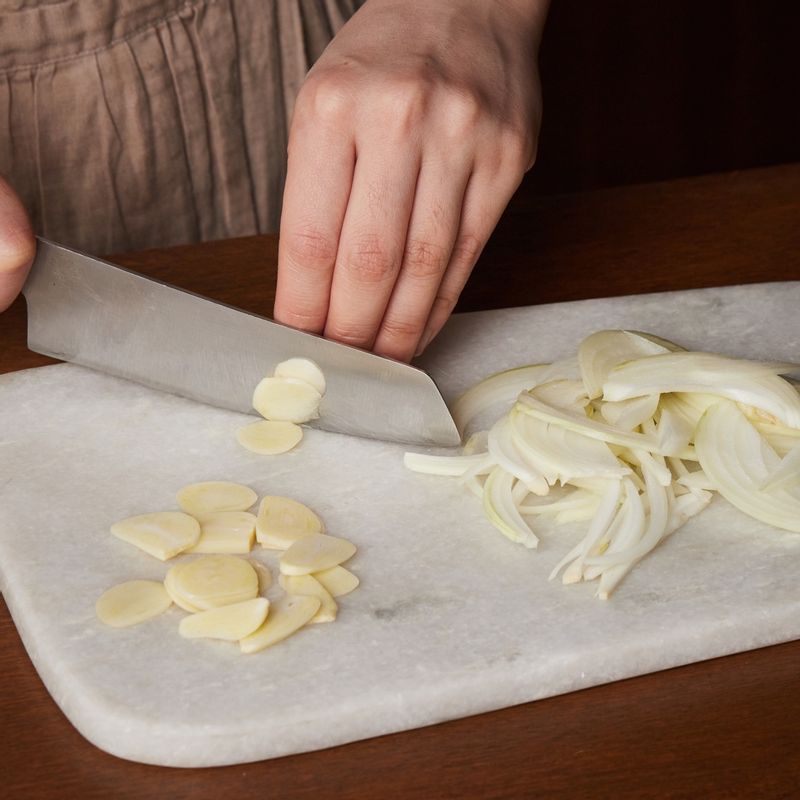 양파는 얇게 채 썰어 주세요. 마늘은 편 썰어 주세요.