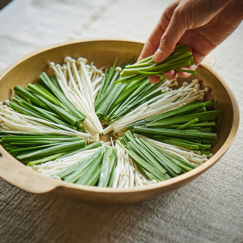 냄비에 부추와 팽이버섯을 돌려 담고, 썰어 놓은 고기를 올려주세요.
