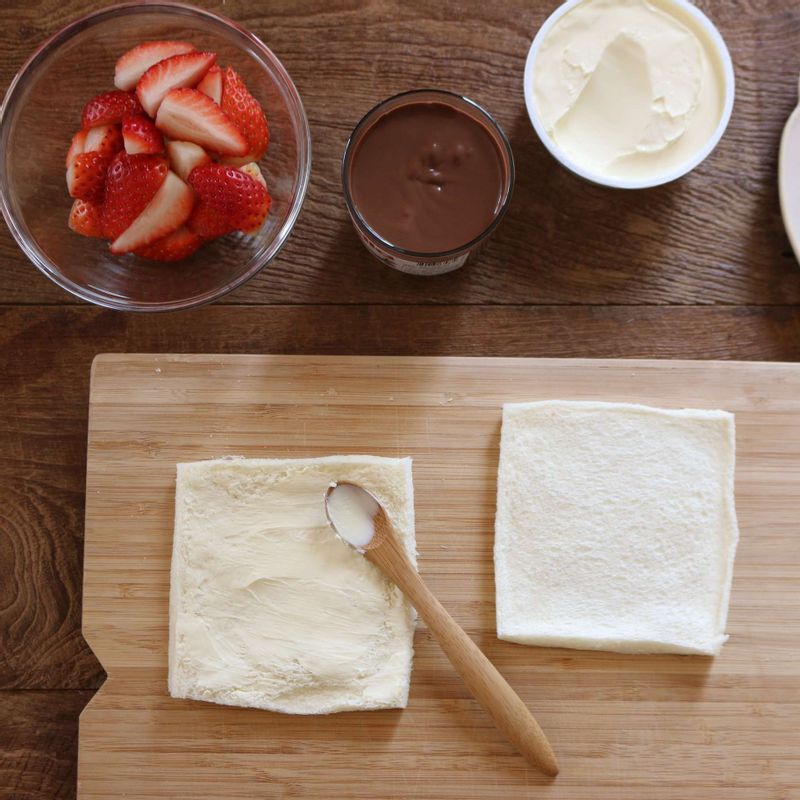 식빵 위에 크림치즈를 펴 바르고, 한쪽 끝에 누텔라-딸기 순으로 올려 돌돌 말아주세요.