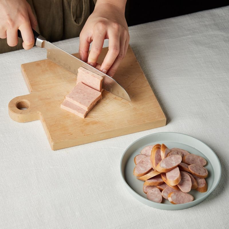 소시지는 두께 0.4cm로 길게 어슷썰고 통조림 햄은 폭 2.5cm 두께 0.5cm로 썰어주세요.