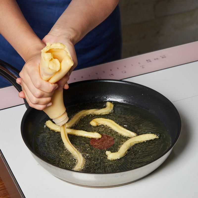 반죽을 약 10cm 길이로 5~6개 정도 짜서 기름에 넣고 젓가락으로 굴려가며 6단에서 5분간 튀겨주세요.