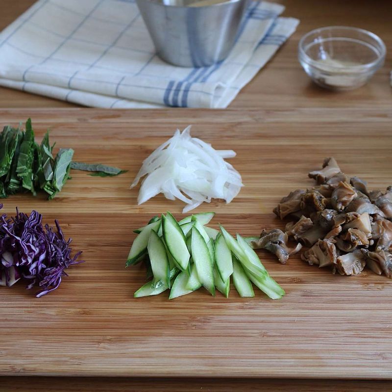 골뱅이는 체에 받쳐 물기를 빼고 4등분으로 잘라주세요. 깻잎과 양파, 적채는 채를 썰고, 오이는 반으로 잘라 어슷하게 썰어주세요.